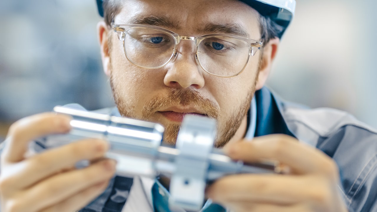 Engineer closely inspecting a mechanical component for quality assurance